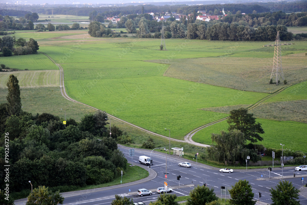 Fototapeta premium Drone view of a road intersection outside the city near a green field with passing cars