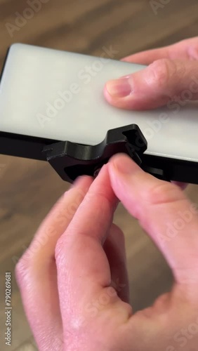 Female hands secure the shoe from the tripod to the LED video light. Video shooting equipment.