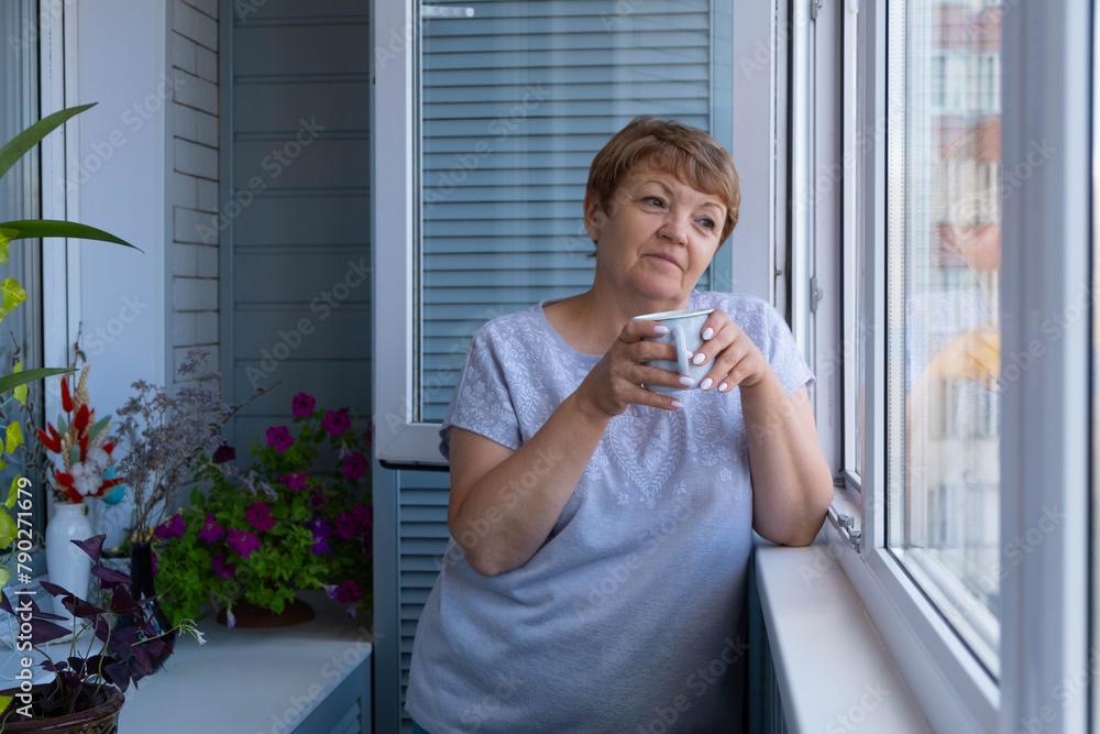 An attractive elderly woman drinks coffee on the balcony. Enjoying life An attractive elderly woman drinks coffee on the balcony. Enjoying life