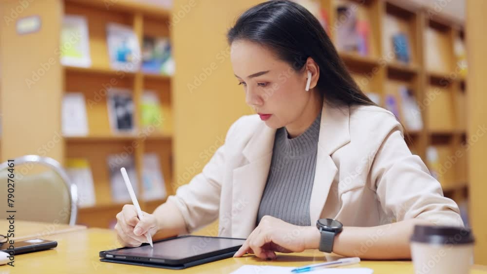 A woman is sitting at a desk with a tablet and a pen. She is writing on a piece of paper A woman is sitting at a desk with a tablet and a pen. She is writing on a piece of paper