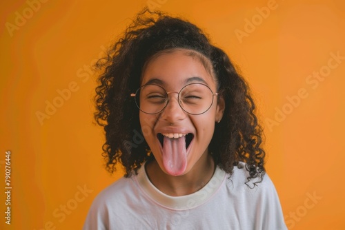 young female nerd sticking out her tongue, her glasses slightly askew, set against a lively orange background to complement her bubbly personality