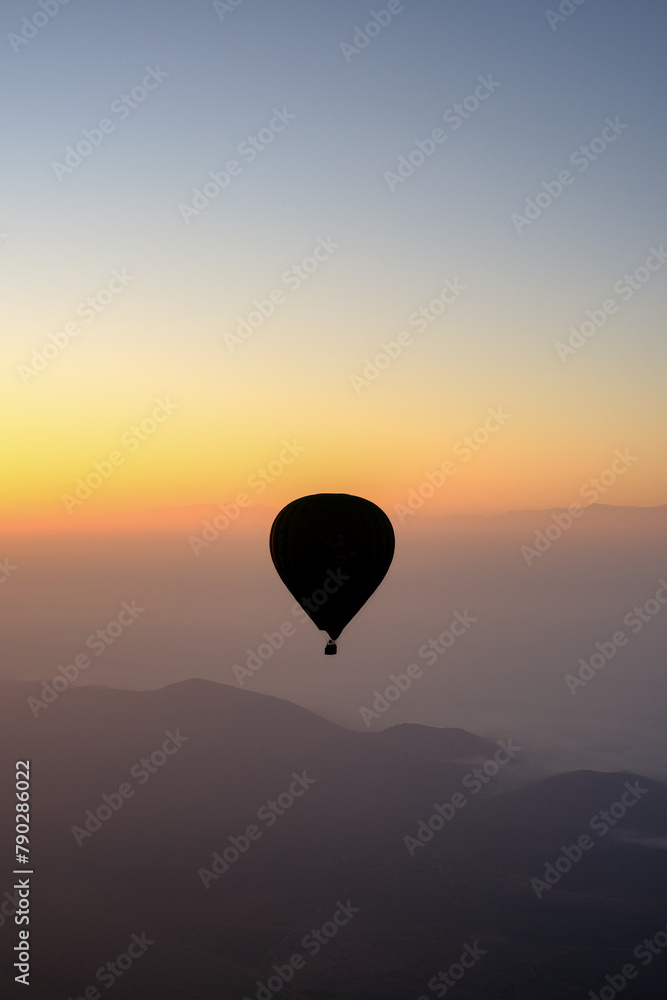 Sunrise in Morocco: A hot air balloon rises over desert dunes, illuminated by the dawn light.