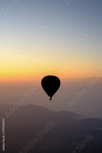 Sunrise in Morocco  A hot air balloon rises over desert dunes  illuminated by the dawn light.