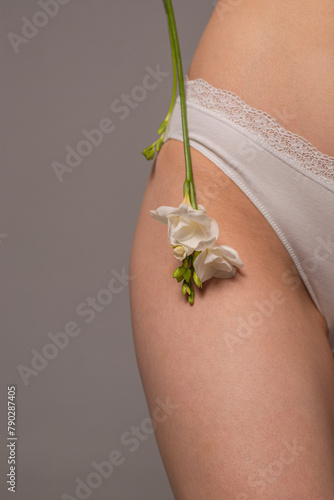 White flower on a woman's thigh. Women's health concept. Youth and beauty. Body care. Natural cosmetics for skin