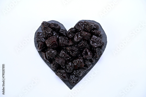 Photography dried plum fruits laid out on a board in the shape of a heart on a white backgro