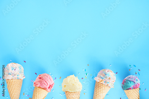 Ice cream cone bottom border over a blue background. Pastel colors. Copy space.