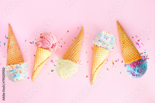 Summer ice cream cone flat lay over a pink background. Assortment of pastel colored flavors.