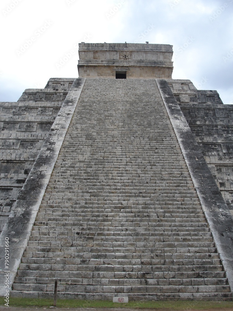 The stairs leading up to the ancient temple of Chichen Itza sit under a cloud sky. The stairs leading up to the ancient temple of Chichen Itza sit under a cloud sky.
