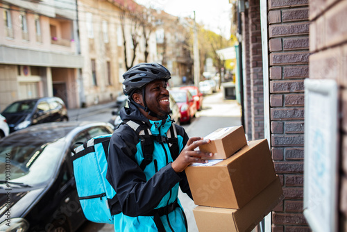 Happy delivery man with a package box on a city street photo