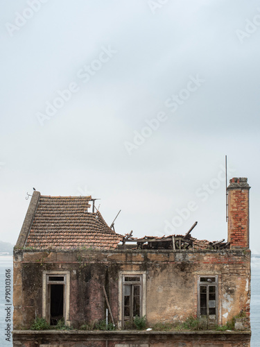 Detail of abandoned dilapidated building. Facade with broken windows, collapsed roof but chimney still standing