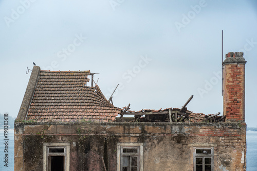 Detail of abandoned dilapidated building. Facade with broken windows, collapsed roof but chimney still standing