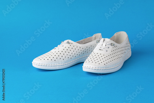 Stylish white athletic shoes on a blue background.