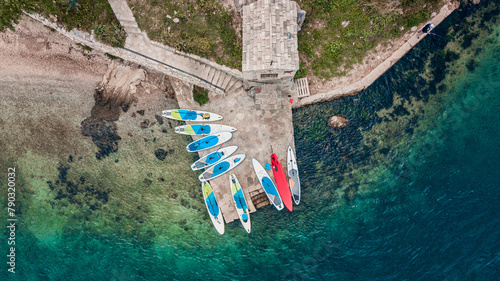 aerial view of colorful stand-up paddleboards lined up on a serene beachfront