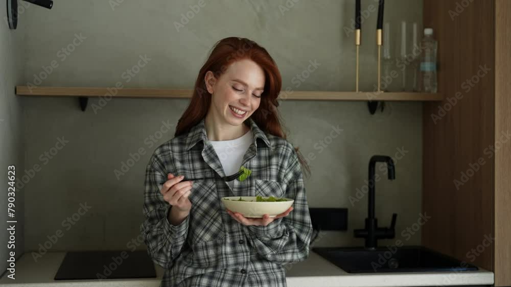 Portrait of young happy woman eating green salad standing in kitchen at home. Attractive beautiful vegetarian female feel happy and enjoy healthy foods for breakfast to lose weight and health care.