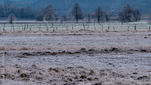 Emty field and fences in early morning with frost on ground