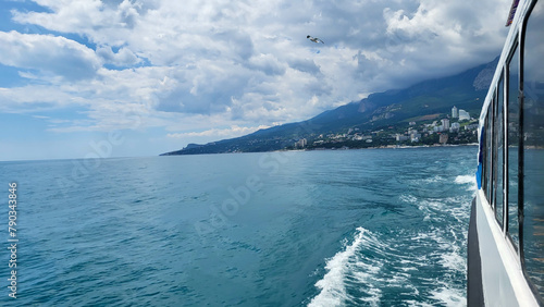 The sky is cloudy, the shore is astern and the blue sea waves. photo
