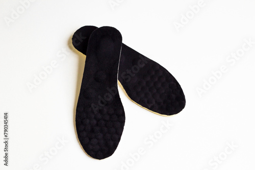 A pair of black colored,orthopedic men's shoe insoles on white surface with copy space photo