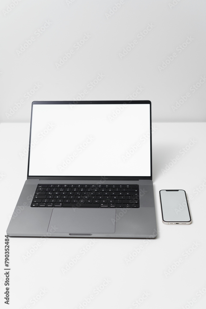 Green laptop screen on white background standing on white desk, laptop screen replacement, home office, work from home, mobile phone with laptop for business, notepad and pen, remote work Green laptop screen on white background standing on white desk, laptop screen replacement, home office, work from home, mobile phone with laptop for business, notepad and pen, remote work