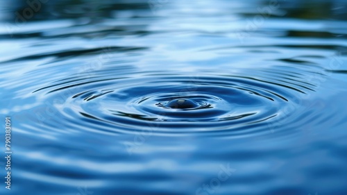 Serene water ripple on a blue pond - A single water droplet creates a ripple in a calm, deep blue pond reflecting the tranquility of nature