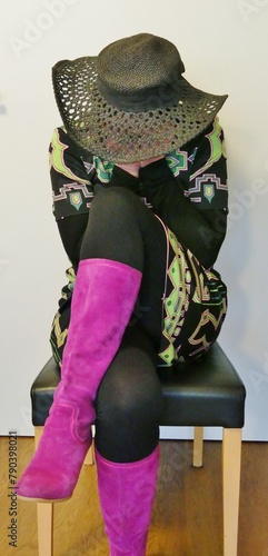 Frau mit 70er-Jahre-Kleid sitzt auf Stuhl