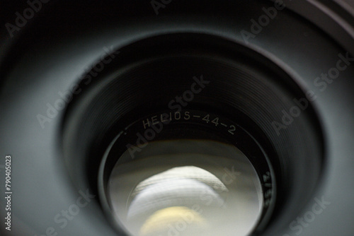 Looking through a Helios 44-2 camera lens, engraved branding on inner rim, highlighting the subtle reflections and contours of the lens interior