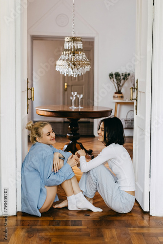 Two women, best friends, sitting at home on the floor, having a fun conversation.