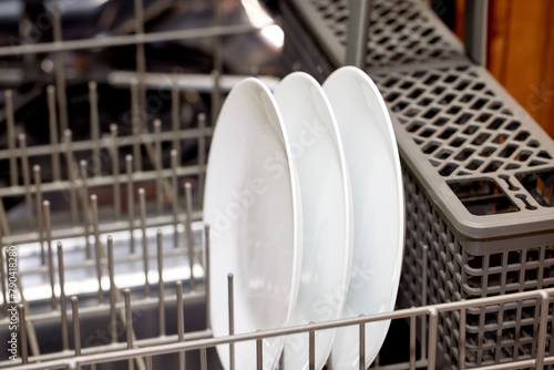 Close up of white ceramic plates in the lower rack of a dishwasher