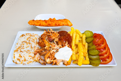 Turkish and Arabic Traditional Ramadan doner kebab with tasty tomato sauce and rice or turkish pilav in white plate on wood table background. ( Pilav ustu doner). Ekmek arasi doner, doner durum.  photo