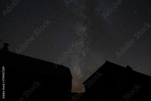 A starry night sky with the Milky Way over some farm buildings