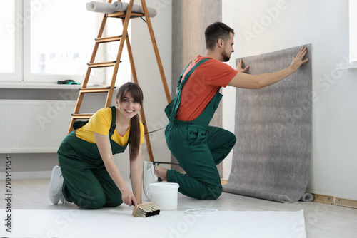 Εκτύπωση καμβά Workers hanging stylish gray wallpaper in room