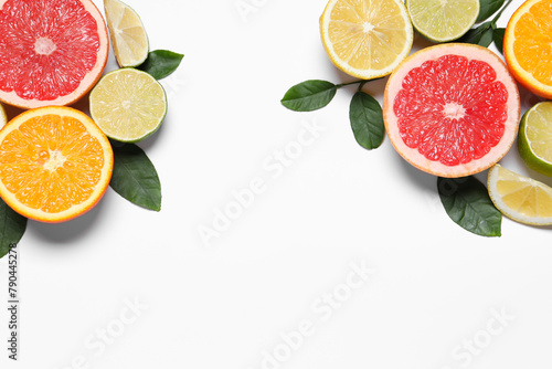 Fototapeta Naklejka Na Ścianę i Meble -  Different cut citrus fruits and leaves on white table, flat lay. Space for text