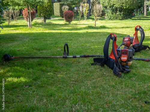 A gardener's lawn mower lies on the grass. Equipment in the park.