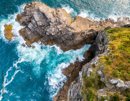 Top view, A rugged coastline seen from above, where cliffs meet the sea in a dramatic collision of land and water.