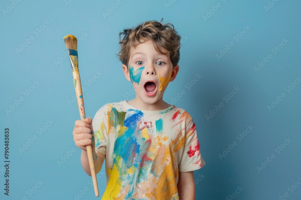 Smiling boy with paintbrush and colorful paint on clothes. Smiling boy with paintbrush and colorful paint on clothes.