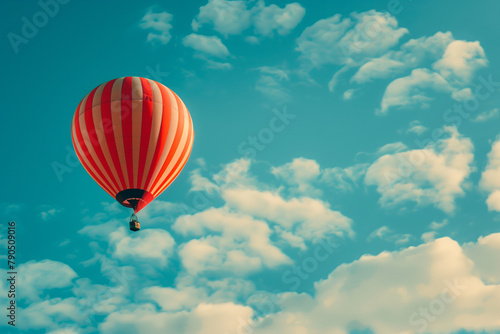 A striped hot air balloon floats in a clear blue sky, offering a sense of adventure against fluffy white clouds