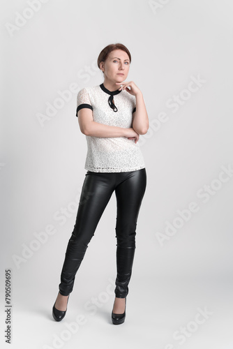 Full length portrait of confident businesswoman looking at camera with one hand raised to chin