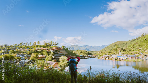 Girl with backpack stand looking forward on beautiful view in lake. Tourist traveler looking sunlight on mountains. Tea plantation in Mae Hong Son.