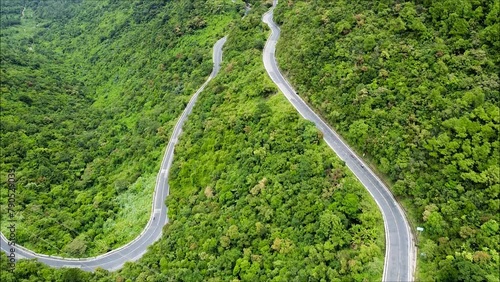 Aerial top down drone shot above the winding mountain road between the trees near Passo Giau in Dolomites, Italy. Overcast late summer weather. Car driving through the curve 4K. Flying straight up photo