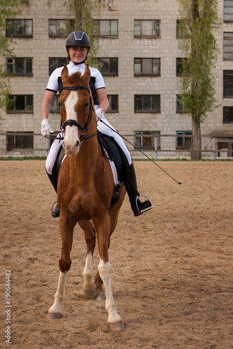 Frontal view of dressage rider on chestnut horse in city arena