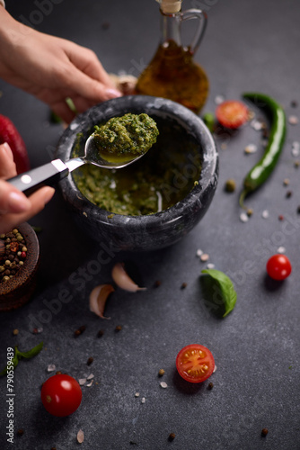 woman mixing green sauce in a stone marble mortar