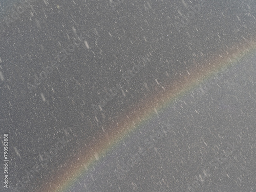 Rainbow on dark sky background during a hailstorm