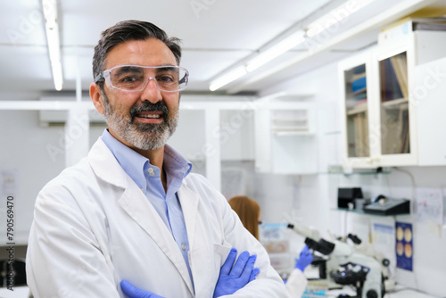 Tablou pe pânză Portrait of a middle aged professional researcher with protective glasses and gloves smiling and looking at camera