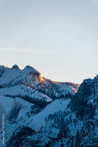 Early sunlight catching the snowcapped mountain tops of the Sierra nevada peaks in Yosemite national park, around sunrise on an early winter morning.