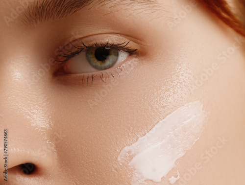 Cream smear. Beauty close up portrait of young woman with a healthy skin is applying a facial skincare product. Face daily care routine 