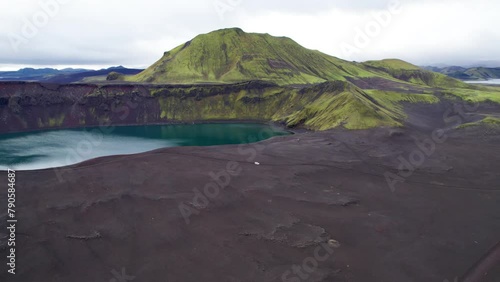 Aerial View White 4x4 Car Driving Offroad Dirt Road Highlands Ljotipollur Crater Iceland. Black Sand Lava Blue Emerald Lake Green Mountain Paradise. 4K High Quality Color Corrected photo
