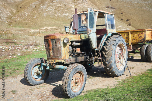 An old vintage tractor on a farm. Non-working condition, rust.