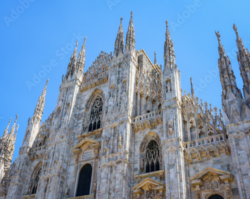 Cathedral Duomo di Milano with spires on Piazza del Duomo square in historical city centre with blue sky background in clear sunny day. Main facade of Milan Cathedral close-up with details