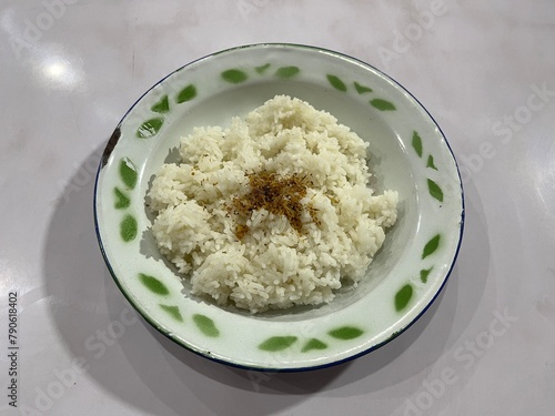 A plate of white rice served with sprinkle of Serundeng which is made from grated and roasted coconut on top