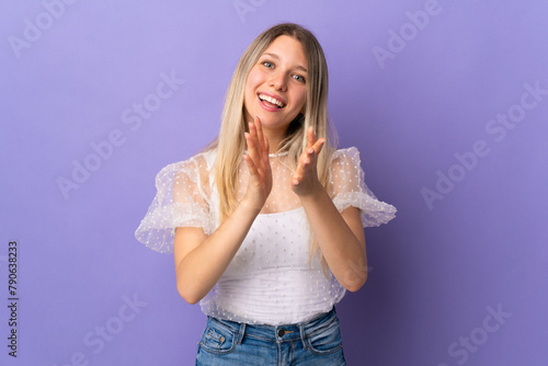 Young blonde woman isolated on purple background applauding after presentation in a conference
