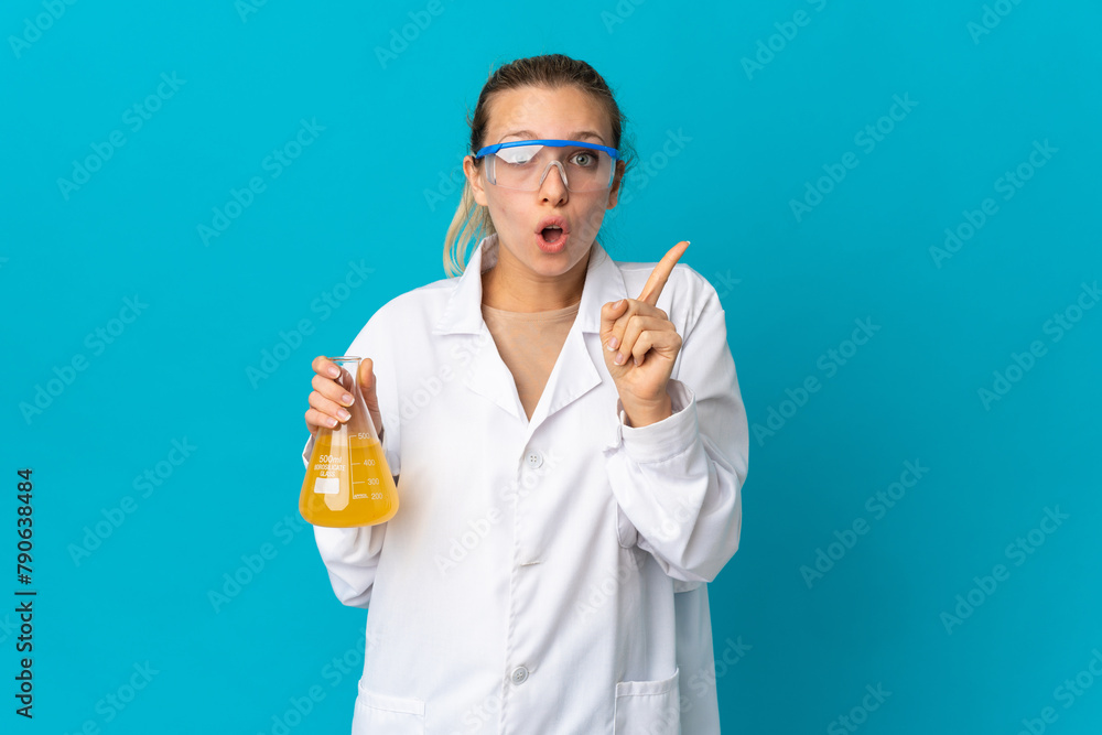 Young scientific woman isolated on blue background intending to realizes the solution while lifting a finger up Young scientific woman isolated on blue background intending to realizes the solution while lifting a finger up